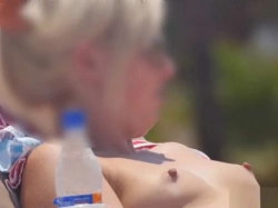 【盗撮動画】真夏のビーチ盗撮。おっぱい丸出しで日光浴してる金髪美女の乳首が常時ピンコ勃ちな件の画像